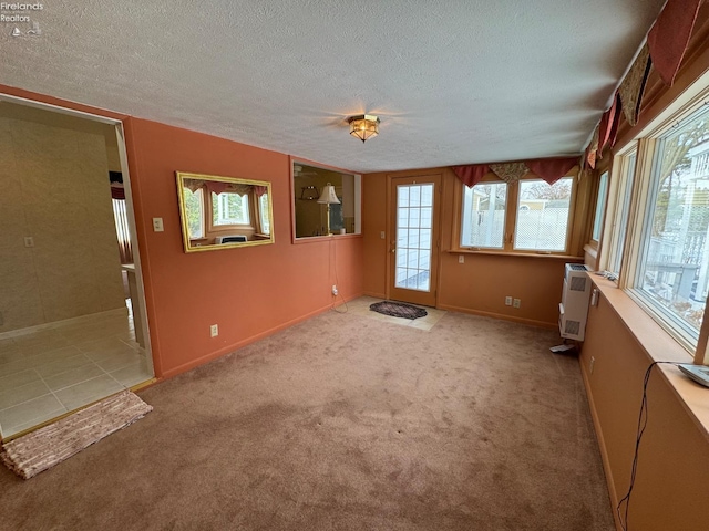 spare room with a textured ceiling, light carpet, and a healthy amount of sunlight