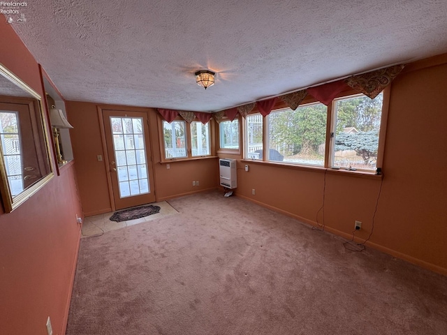 spare room with heating unit, light colored carpet, and a textured ceiling