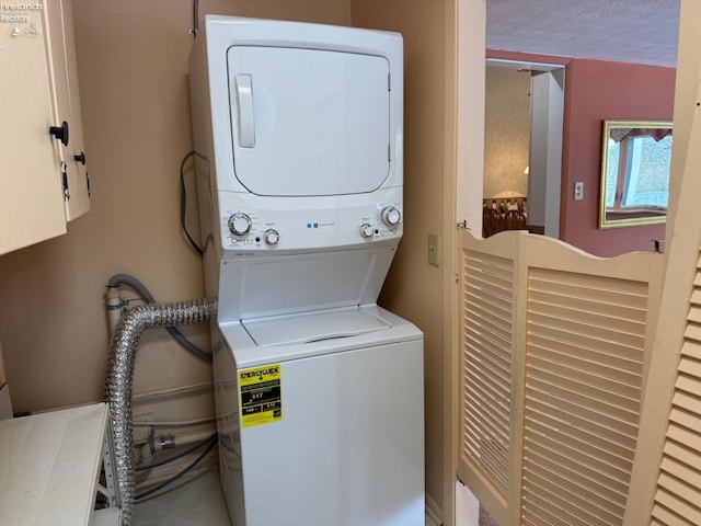 washroom featuring a textured ceiling and stacked washer and dryer