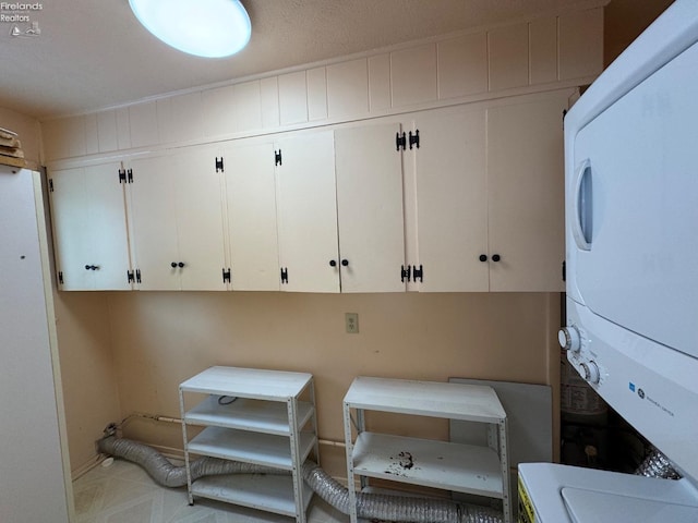 washroom featuring stacked washer / dryer and cabinets