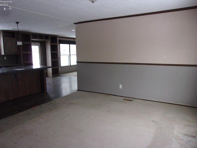 kitchen featuring hanging light fixtures, a textured ceiling, and dark colored carpet