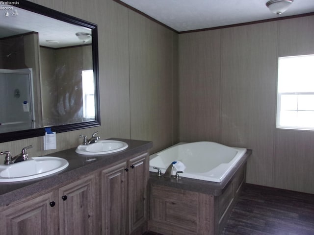 bathroom with hardwood / wood-style flooring, ornamental molding, vanity, and a tub