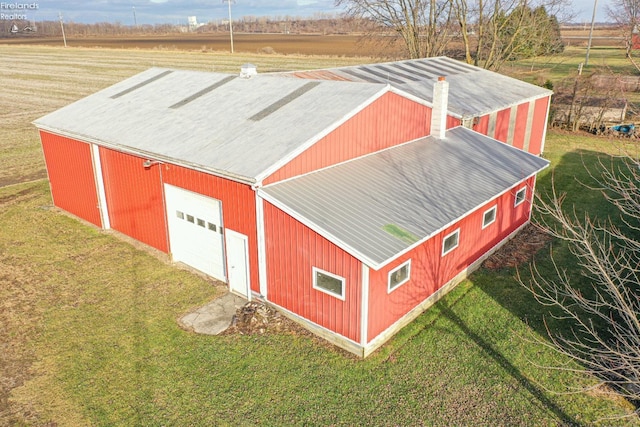 view of outbuilding with a garage, a yard, and a rural view