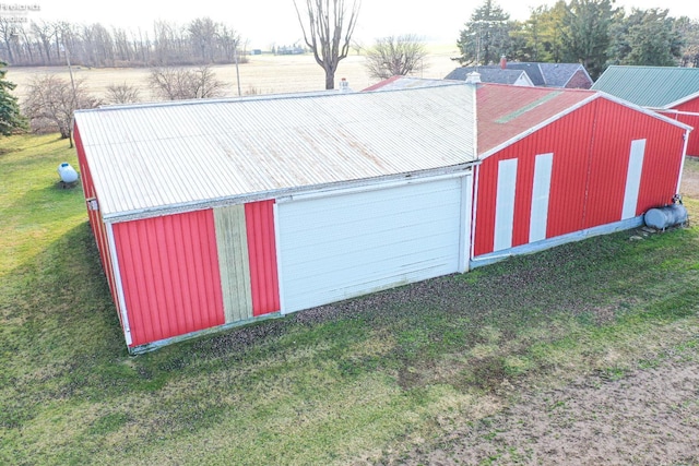 garage with a rural view and a lawn