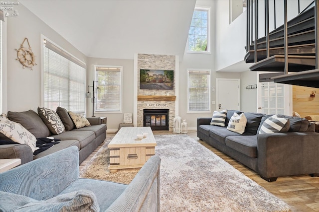 living room with light wood-type flooring, a fireplace, and a towering ceiling