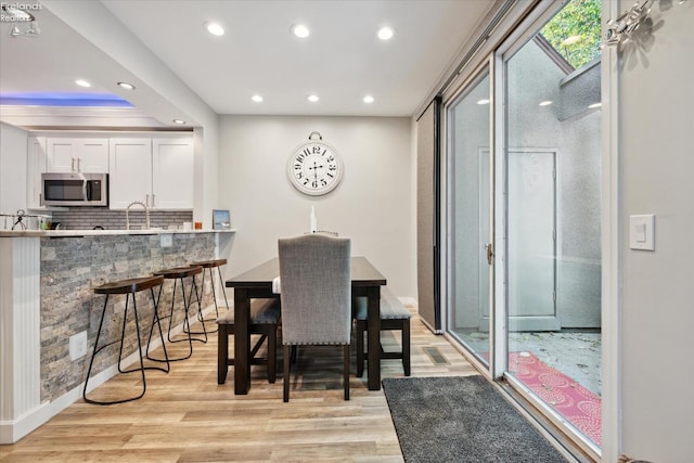 dining area with crown molding, sink, and light hardwood / wood-style floors