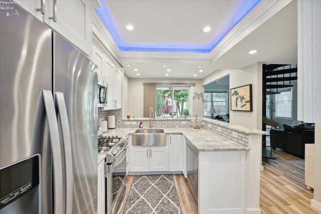 kitchen featuring sink, white cabinetry, light stone counters, appliances with stainless steel finishes, and kitchen peninsula