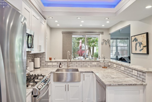 kitchen with sink, white cabinetry, light stone counters, kitchen peninsula, and stainless steel appliances