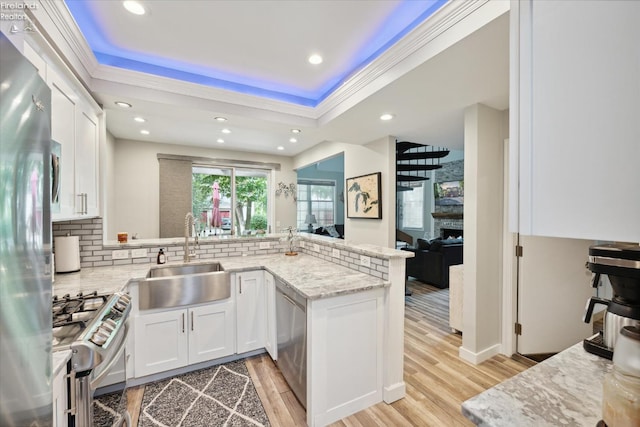 kitchen featuring sink, white cabinets, kitchen peninsula, stainless steel appliances, and light wood-type flooring