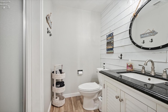 bathroom with vanity, wood-type flooring, wooden walls, and toilet