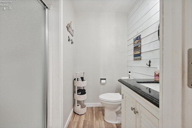 bathroom with a shower with door, vanity, hardwood / wood-style floors, and toilet