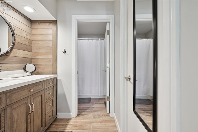 bathroom with hardwood / wood-style flooring, vanity, and wooden walls