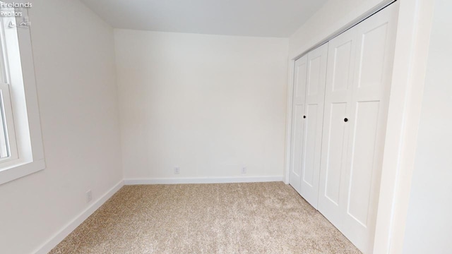 unfurnished bedroom with a closet and light carpet