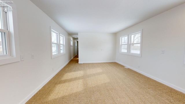 unfurnished room with light colored carpet and a healthy amount of sunlight