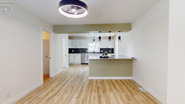 kitchen featuring white cabinetry, sink, decorative backsplash, hanging light fixtures, and stainless steel dishwasher