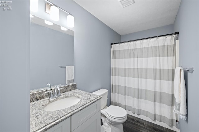 full bathroom with vanity, hardwood / wood-style floors, toilet, and shower / bath combo