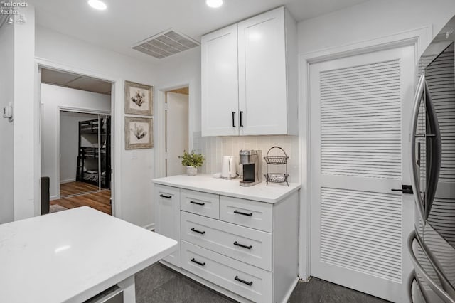 kitchen featuring white cabinetry, dark wood-type flooring, stainless steel refrigerator, and decorative backsplash