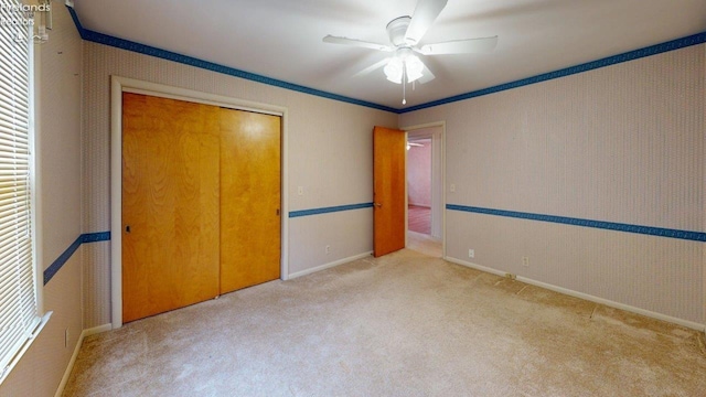 unfurnished bedroom with ceiling fan, ornamental molding, light carpet, and a closet