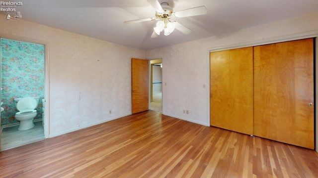 unfurnished bedroom featuring ceiling fan, ensuite bathroom, a closet, and light hardwood / wood-style flooring