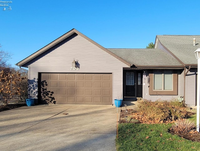 ranch-style house featuring driveway, roof with shingles, and an attached garage