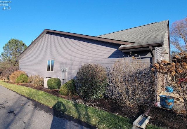 view of side of home with a shingled roof