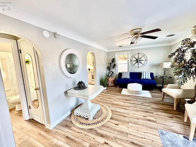 bedroom with ceiling fan, connected bathroom, and light hardwood / wood-style flooring