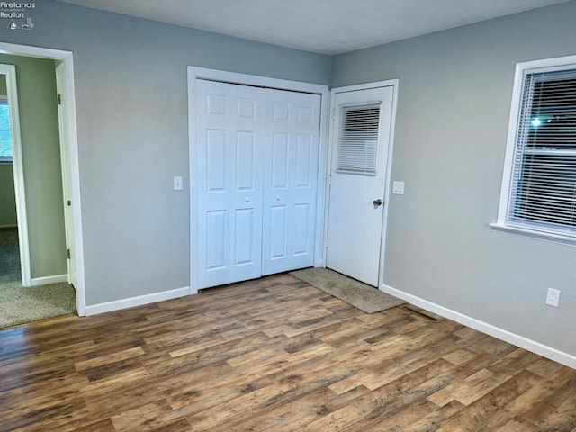 unfurnished bedroom with a closet and dark hardwood / wood-style floors