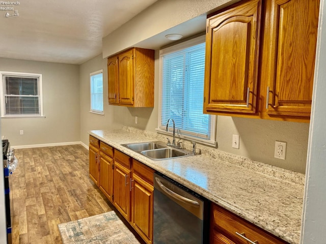 kitchen featuring appliances with stainless steel finishes, light stone countertops, sink, and light wood-type flooring