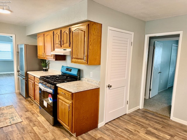 kitchen with appliances with stainless steel finishes, light hardwood / wood-style flooring, and a textured ceiling