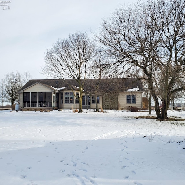 snow covered house featuring a sunroom