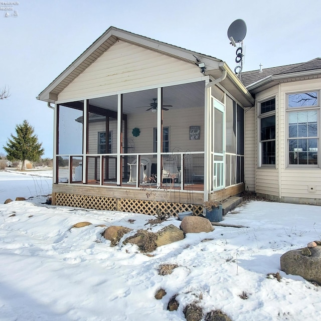 snow covered house featuring ceiling fan