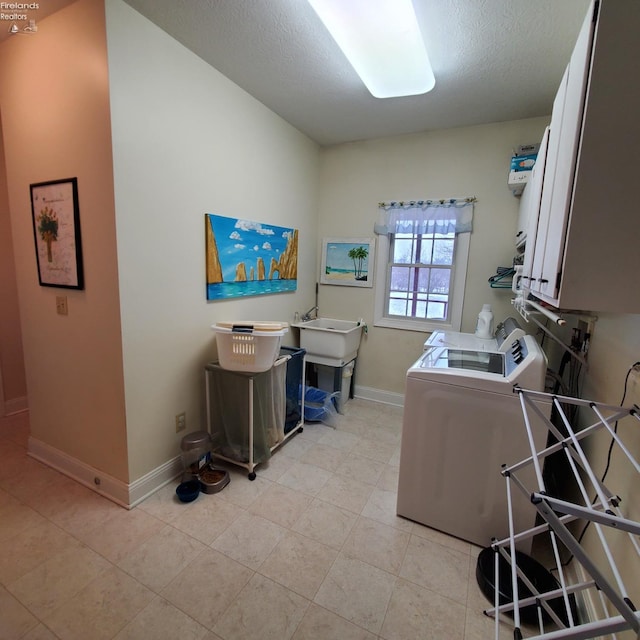 clothes washing area featuring washer and dryer, cabinets, and a textured ceiling