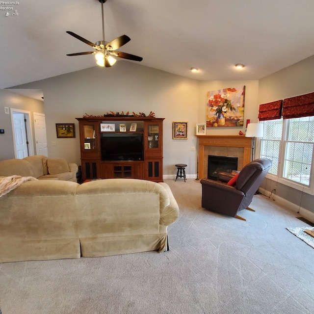 carpeted living room featuring a tiled fireplace, vaulted ceiling, and ceiling fan