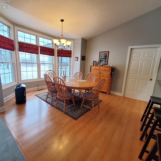 dining space featuring lofted ceiling, a notable chandelier, and light wood-type flooring