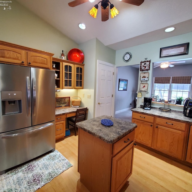 kitchen featuring built in desk, stainless steel fridge, a kitchen island, ceiling fan, and light hardwood / wood-style floors