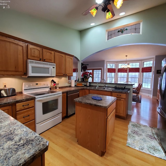 kitchen with appliances with stainless steel finishes, sink, hanging light fixtures, a center island, and kitchen peninsula