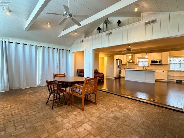 dining space featuring ceiling fan, high vaulted ceiling, beam ceiling, and sink