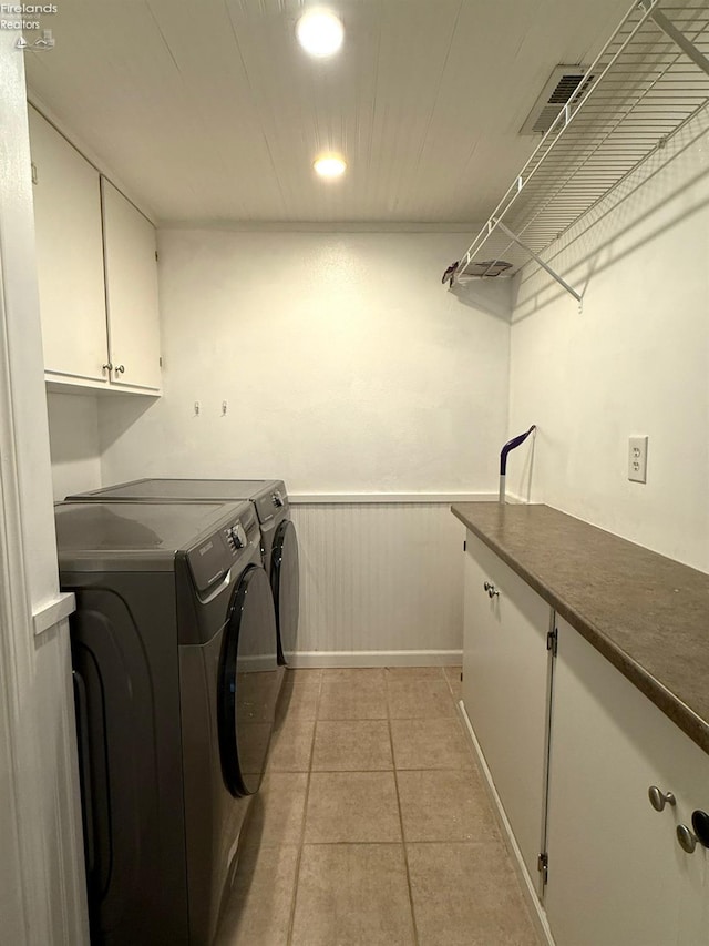 washroom featuring independent washer and dryer, cabinets, and light tile patterned floors