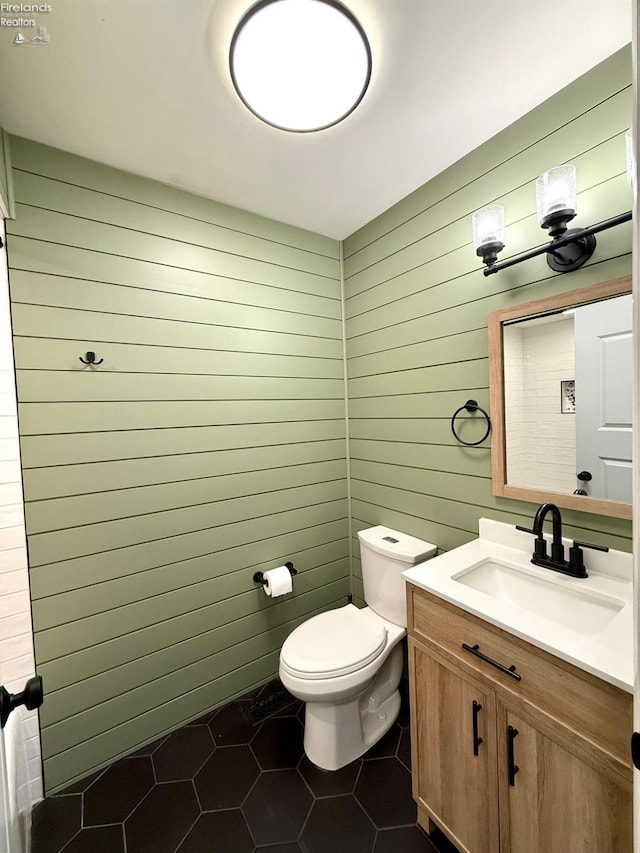 bathroom with vanity, tile patterned flooring, toilet, and wood walls