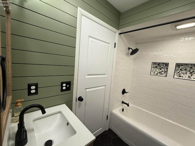 bathroom featuring tiled shower / bath combo, vanity, tile patterned floors, and wooden walls