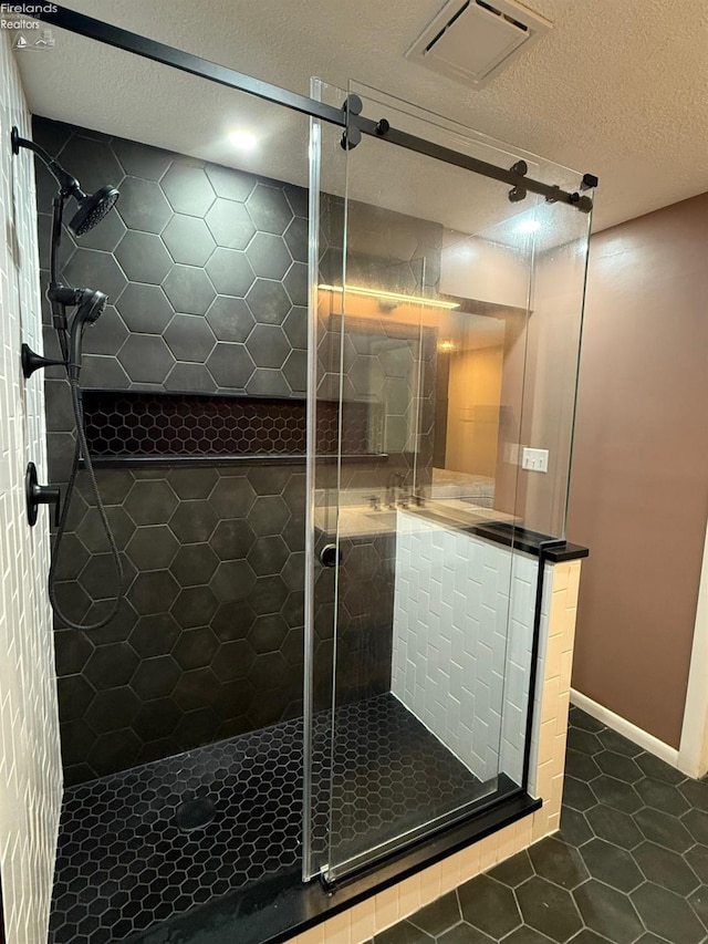 bathroom with tile patterned floors, an enclosed shower, and a textured ceiling