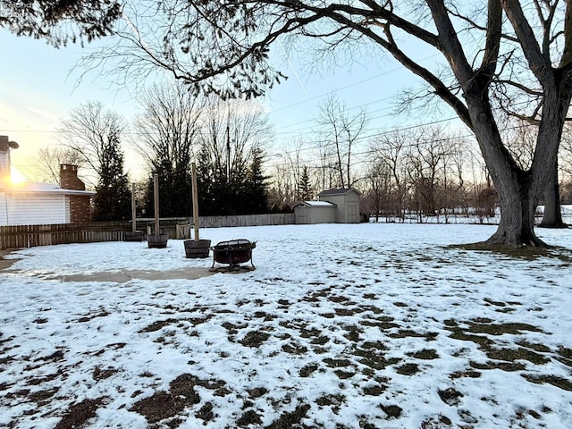 snowy yard featuring an outdoor fire pit and a shed