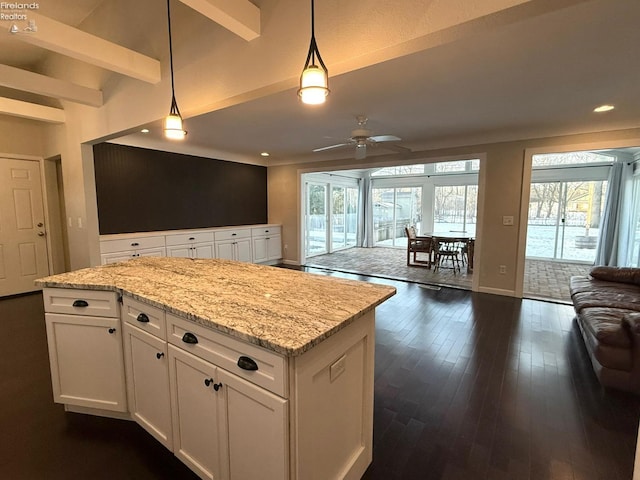 kitchen featuring dark hardwood / wood-style flooring, white cabinets, light stone counters, and decorative light fixtures