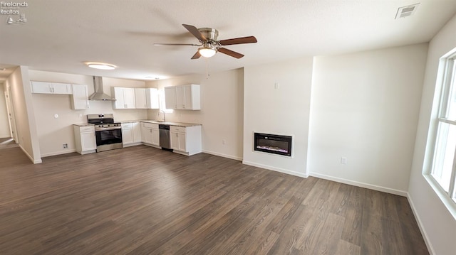 kitchen with appliances with stainless steel finishes, sink, wall chimney range hood, and white cabinets