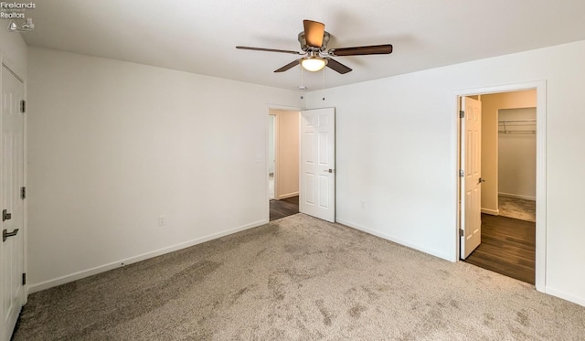 unfurnished bedroom featuring a walk in closet, carpet, ceiling fan, and a closet