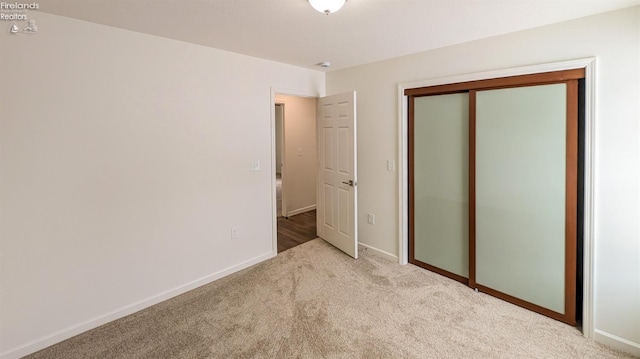 unfurnished bedroom with light colored carpet and a closet