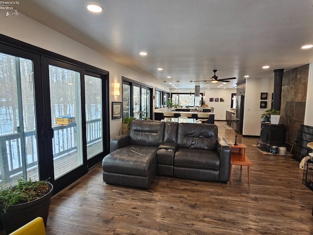 living room featuring ceiling fan, a wood stove, and dark hardwood / wood-style flooring