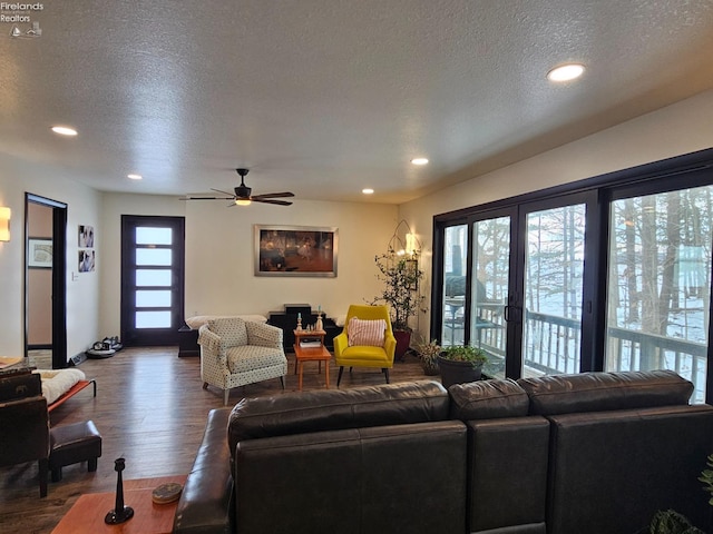 living room featuring ceiling fan, a healthy amount of sunlight, dark hardwood / wood-style flooring, and a textured ceiling