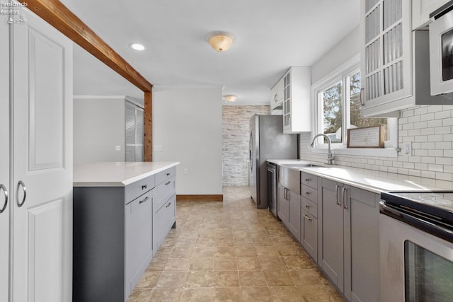 kitchen featuring tasteful backsplash, appliances with stainless steel finishes, sink, and gray cabinetry