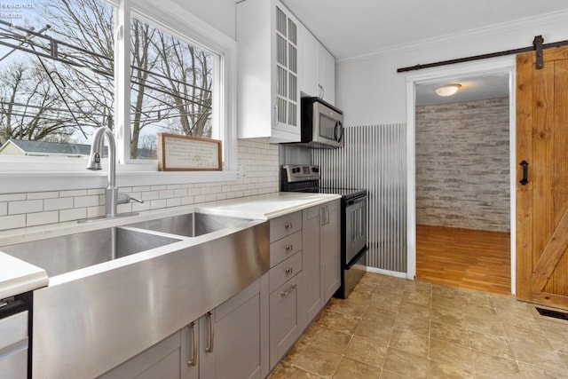 kitchen with white cabinetry, crown molding, gray cabinets, stainless steel appliances, and a barn door